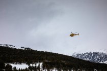 Rescue helicopter flying flying over mountain woods — Stock Photo