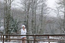 Donna allegra in accappatoio in piedi al fiume nella foresta invernale . — Foto stock