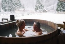 Sensual mature couple sitting in plunge tub in winter. — Stock Photo