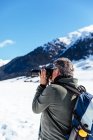Side view of photographer taking pictures of mountains in snow — Stock Photo