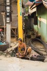 LAOS- 20 DE FEBRERO DE 2018: Pobre mujer asiática sin hogar sentada y apoyada en el poste al borde de la carretera . - foto de stock