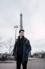 Junger Mann mit Brille posiert vor dem Hintergrund des Eiffelturms. — Stockfoto