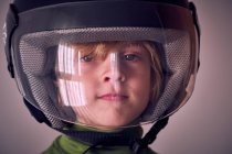 Милый мальчик в мотоциклетном шлеме смотрит в камеру — стоковое фото