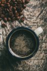 Taza de café por granos de café sobre fondo oscuro - foto de stock