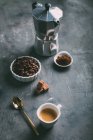 Natureza morta da cafeteira, xícara de café expresso e ingredientes na mesa — Fotografia de Stock