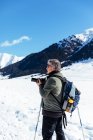 Зрелый фотограф фотографирует на снежном лугу — стоковое фото