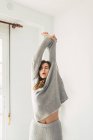 Giovane donna che si toglie i vestiti grigi in appartamento . — Foto stock