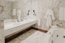 Interior de baño de lujo con espejo grande y paredes de baldosas de mármol - foto de stock