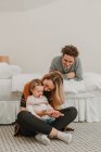 Cheerful couple with child chilling on bed — Stock Photo