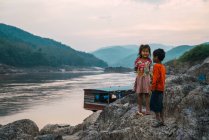 LAOS- 18 FÉVRIER 2018 : Mignon garçon et fille debout sur le rocher à la rivière . — Photo de stock