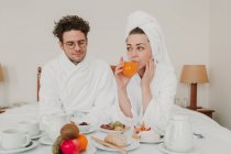 Giovane coppia che fa colazione nel letto dell'hotel — Foto stock