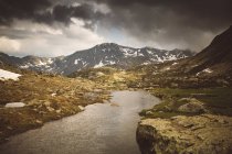 View to small river flowing in mountain valley in cloudy day. — Stock Photo