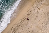 Прямо над видом бегуна бегущего по океанскому пляжу — стоковое фото