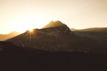 Montagnes rétroéclairées au coucher du soleil dans un ciel dégagé . — Photo de stock