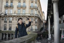 Jovem homem alegre tomando selfie no terraço da rua — Fotografia de Stock