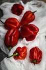 Natureza morta de pimentas vermelhas frescas em tecido branco rural — Fotografia de Stock