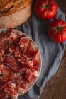 Spanischer Schinken mit Tomaten und Brot auf Leinwand — Stockfoto