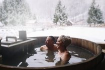 Веселый взрослый мужчина и женщина купаются в ванной на открытом воздухе — стоковое фото