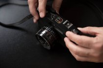 Crop hands taking vintage camera on black background — Stock Photo