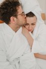 Romantisches Paar im Bademantel umarmt sich auf dem Bett — Stockfoto