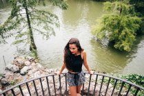 Brunette woman leaning on handrail at river. — Stock Photo