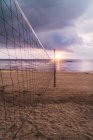 Volleyballnetz am Sandstrand bei Sonnenuntergang — Stockfoto