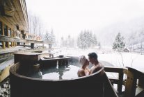 Paar küsst sich in Badewanne in Winterlandschaft — Stockfoto