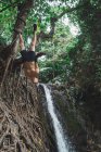 Cheerful man hanging upside down on tree over forest river — Stock Photo