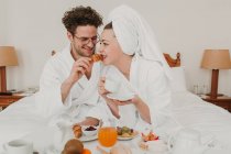 Couple joyeux petit déjeuner dans le lit de l'hôtel — Photo de stock