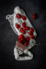 Still life of fresh red peppers and sieve on rural white fabric — Stock Photo