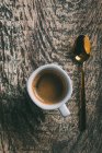 Direkt über Blick auf Kaffeetasse und Löffel auf rustikalem Holztisch — Stockfoto