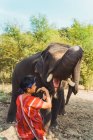 Chiang rai, thailand - 12. Februar 2018: fröhlicher Mann füttert Elefanten mit Früchten in der Natur. — Stockfoto