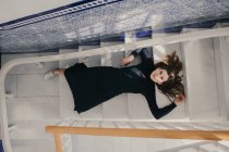 From above  view of woman lying on steps and looking at camera. — Stock Photo