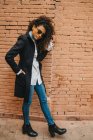 Stylish curly woman posing at brick wall — Stock Photo