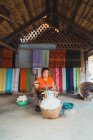 LAOS- FEBRERO 18, 2018: Mujer sonriente trabajando con tela en el patio - foto de stock