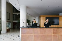 Pretty staff women standing at counter on reception in hotel — Stock Photo