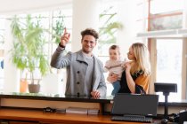 Happy family calling staff while standing at reception in hotel. — Stock Photo