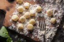 Raw gnocchi in flour by fork on boards — Stock Photo