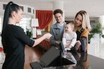 Staff worker giving key to young family at hotel reception — Stock Photo