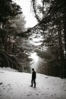 Tourist walking in snowy forest and looking over shoulder away — Stock Photo