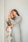 Чувственная молодая женщина, обнимающая оранжевые цветы в вазе с закрытыми глазами — стоковое фото