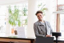 Smiling man in glasses standing at reception in hotel. — Stock Photo