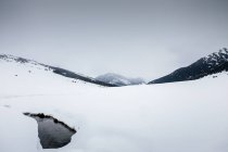 Снежный пейзаж горной долины над туманной вершиной и серым небом — стоковое фото
