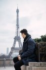 Giovane uomo appoggiato sullo sfondo della torre Eiffel . — Foto stock