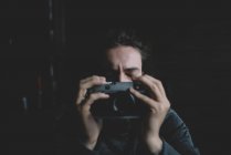 Fotografo posa con gli occhi chiusi e tenendo fotocamera vintage — Foto stock