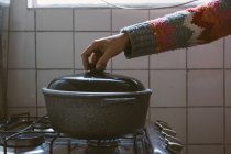 Crop mão feminina segurando tampa da panela no fogão — Fotografia de Stock