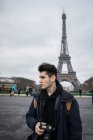Jeune touriste avec caméra marchant près de la tour Eiffel . — Photo de stock