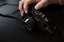 Manos recortadas ajustando la cámara vintage sobre fondo negro - foto de stock