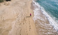 Высокий угол обзора бегущей женщины на пляже — стоковое фото