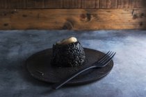 Schwarzer Reis mit Tintenfisch auf schwarzem Teller — Stockfoto